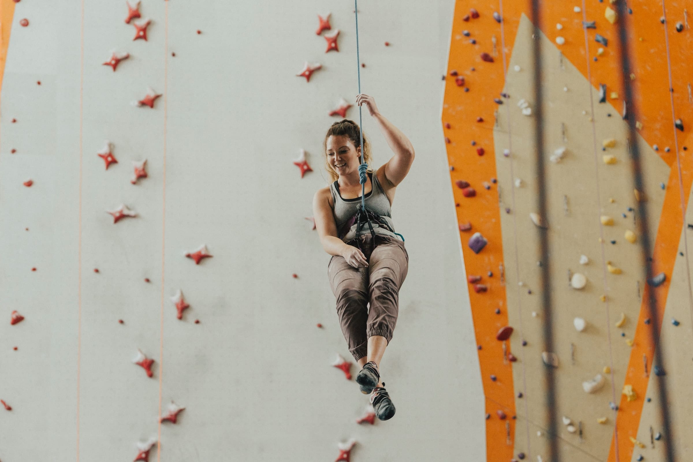 Smiling woman descending from a climbing wall